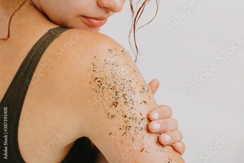 Woman using body scrub on white background.