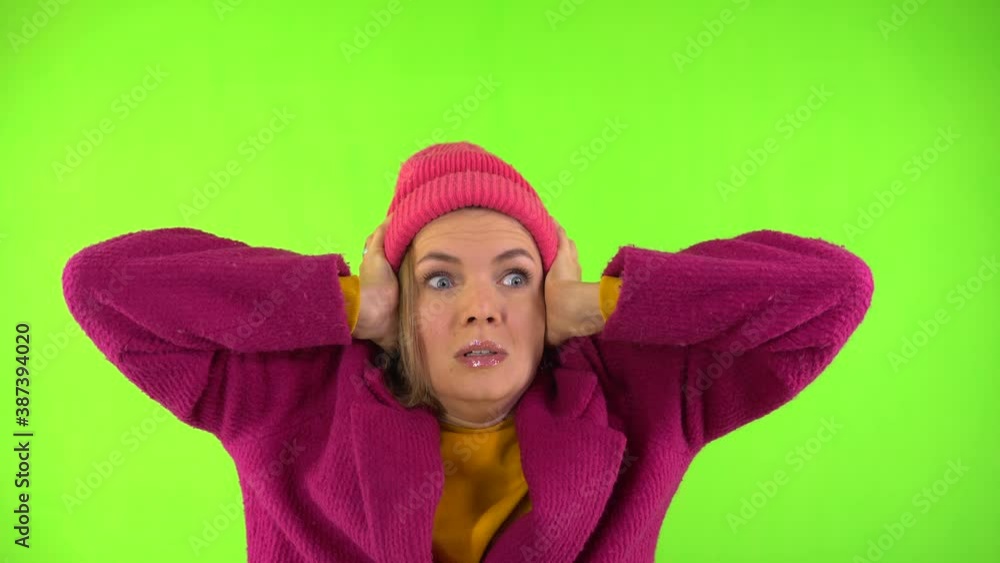 Pretty Woman in Little Red Riding Hood and Red Coat is Afraid and Closes Her Ears. Studio Video Footage, Green Background, Isolate. Pretty Woman in Little Red Riding Hood and Red Coat is Afraid and Closes Her Ears. Studio Video Footage, Green Background, Isolate.