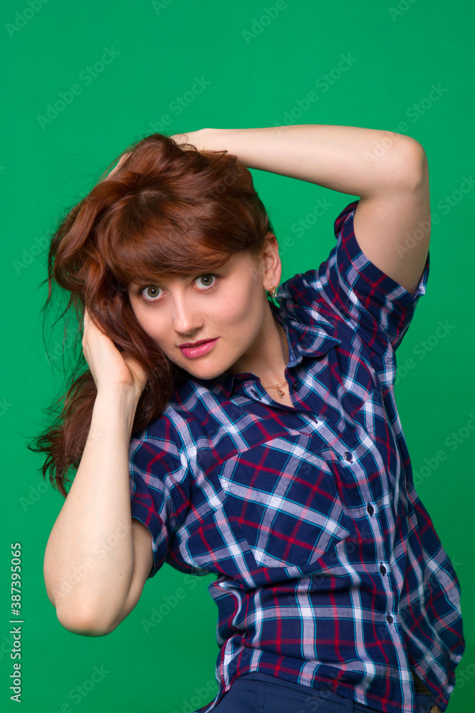 Beautiful girl with brown hair in a plaid shirt on a green background in the studio