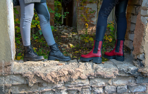 The girls ' feet stand on the windowsill of a dilapidated abandoned building.