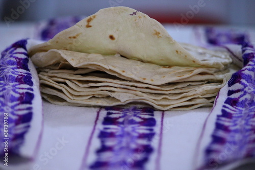 tortillas de harina apiladas en una servilleta bordada con detalles morados  photo