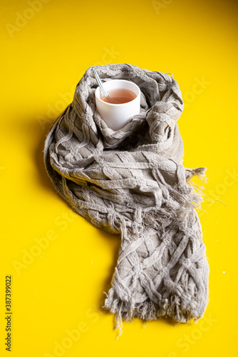 Fototapeta Naklejka Na Ścianę i Meble -  A cup of hot tea wrapped in a scarf