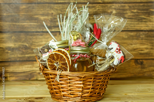 Christmas food gift basket. Edible Christmas gift made of cookies, honey, homemade handmade sweets, dried oranges, lollipops on a wooden table.Concept handmade christmas gifts, Handmade food presents