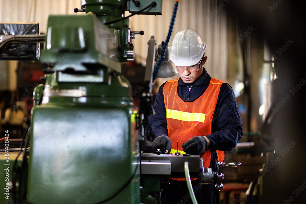 Mechanical Engineering control lathe machine in factory facility. Safety First at work place. Man Worker at industrial factory wearing uniform and hardhats. Mechanical Engineering control lathe machine in factory facility. Safety First at work place. Man Worker at industrial factory wearing uniform and hardhats.