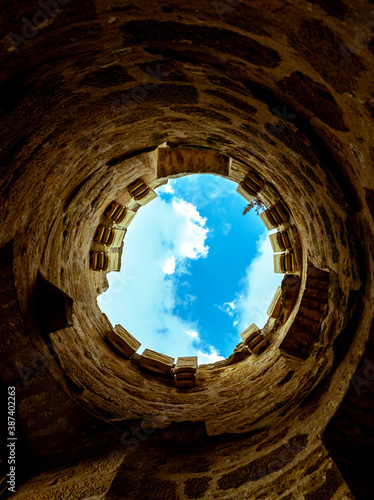 looking up to the sky or at the end of the tunnel there is a light  foreground tunnel and background the blue sky with clouds 