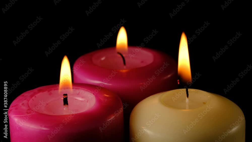 Large thick candles are lit and burn on a black background high resolution video clip macro shooting close-up