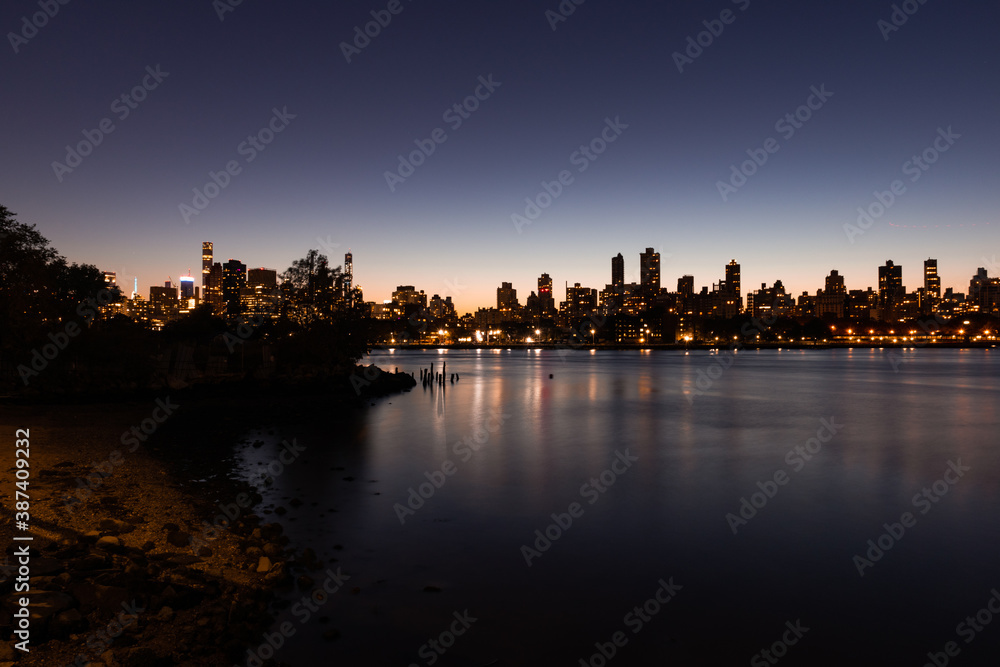 Upper East Side and Manhattan Skyline at Night along the East River in New York City seen from the Shore of Astoria Queens
