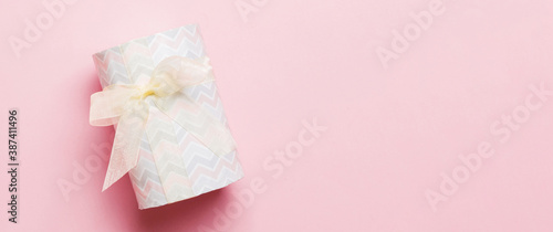 Top view Christmas present box with yellow bow on pink background with copy space © sosiukin