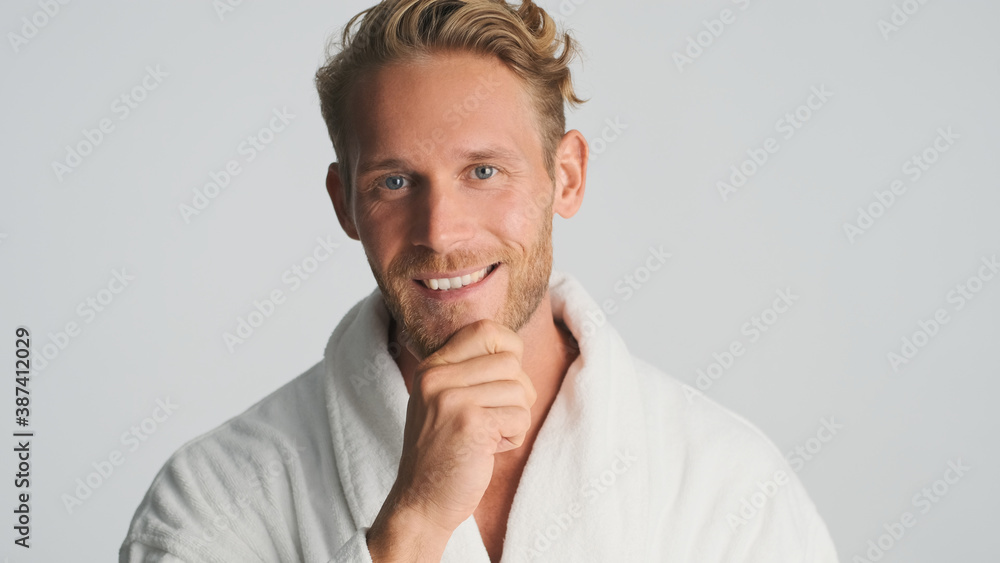 Handsome smiling bearded man in bathrobe looking happy on camera isolated on white background