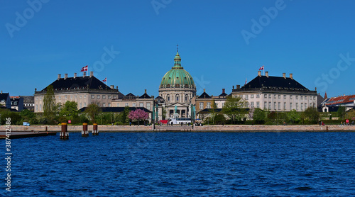 Front view from water of royal Amalienborg castle with church Frederiks Kirke in the center in Copenhagen, Denmark on sunny day in spring with blue sky.