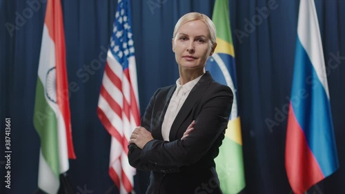 Wallpaper Mural Medium portrait shot of elegant Caucasian female politician with blond hair standing against flags crossing her arms Torontodigital.ca