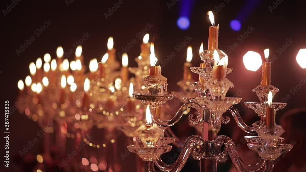 Candlestick with burning candles on the festive table, low light background