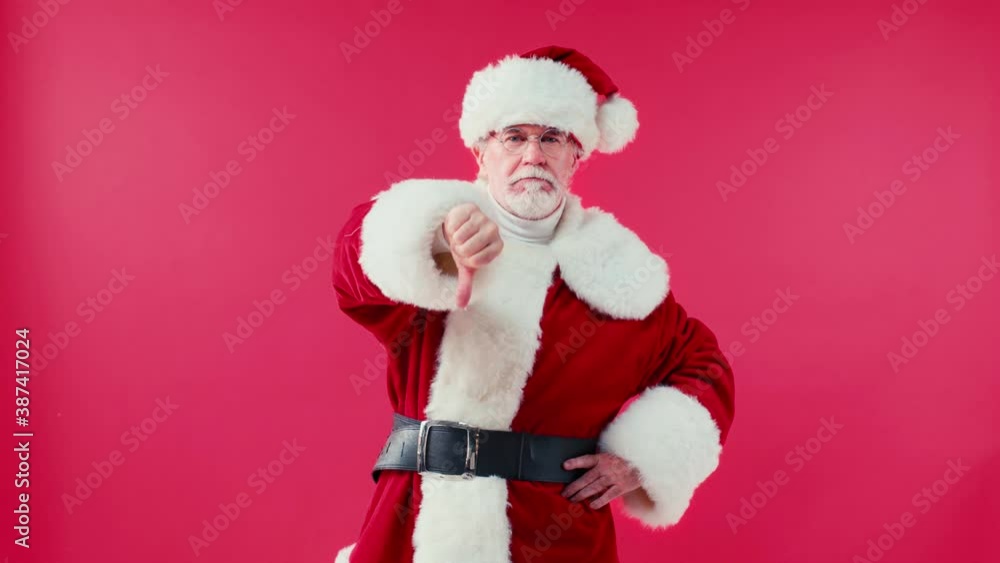 displeased santa claus with hand on hip showing thumb down isolated on red displeased santa claus with hand on hip showing thumb down isolated on red