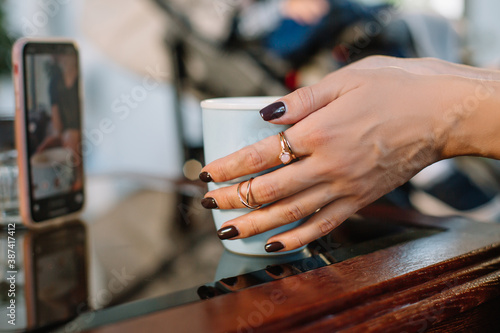Blue cup of coffee in female hands with painted nails