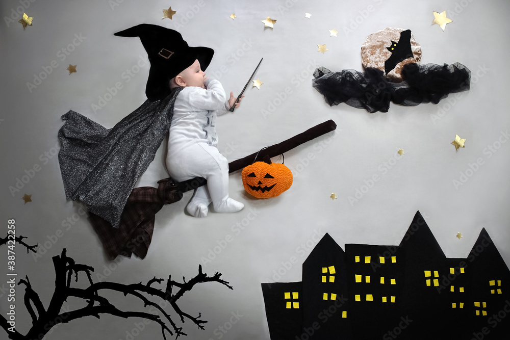 Halloween party baby on broom in wizard hat, magic wand flying to the moon with bat over night city flat lay - obrazy, fototapety, plakaty 
