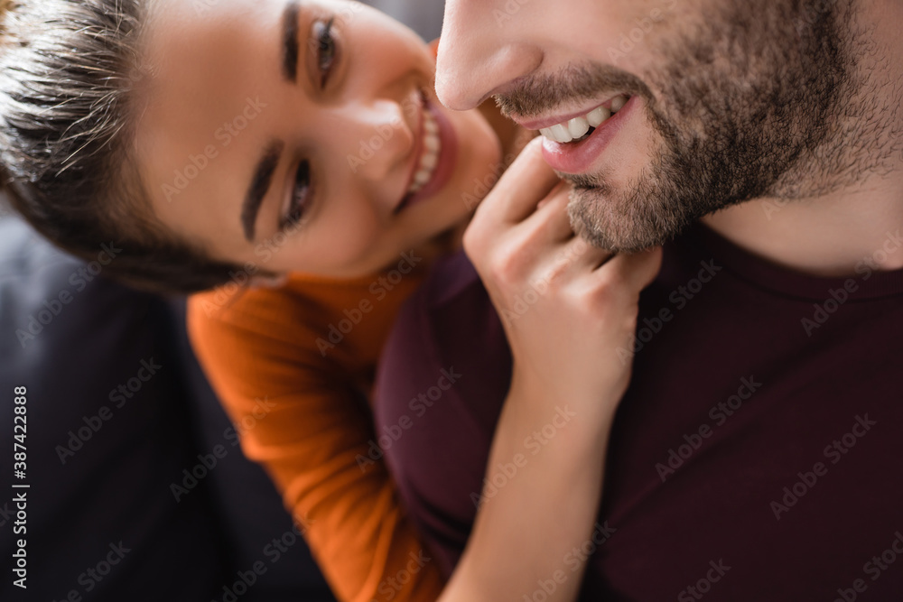 smiling woman touching face of happy man on blurred background smiling woman touching face of happy man on blurred background