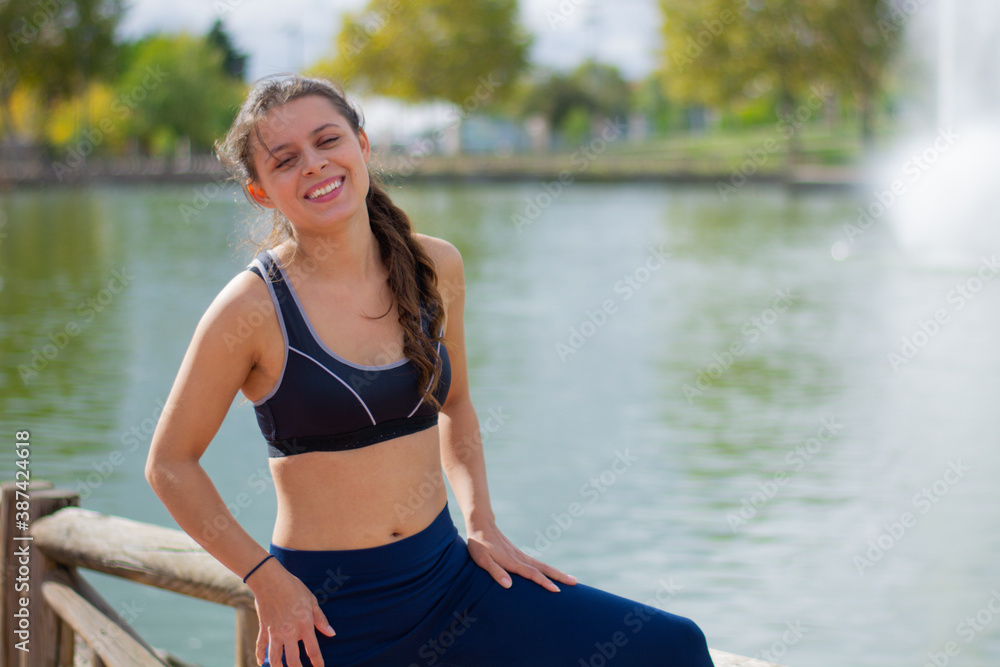 Foto de Instructor de fitness mujer delgada hermosa caucásica agua potable  durante los ejercicios de entrenamiento al aire libre. mujer en ropa  deportiva do Stock