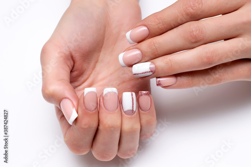 French wedding white manicure with pink glittery stripe and shiny little finger on long square nails close-up on white background