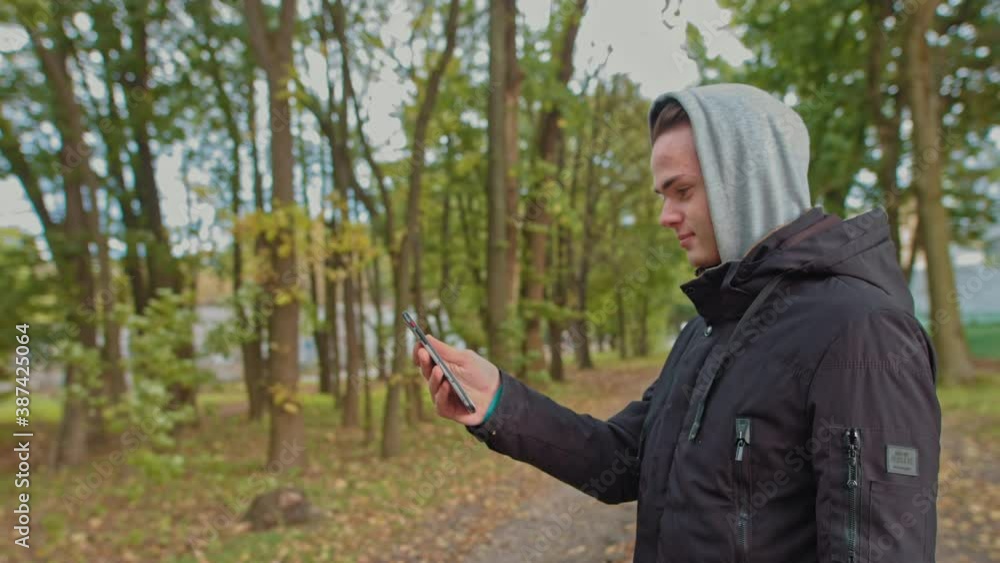 Nomophobia - People using the mobile phone. No-mobile-phone phobia. young guy talking on a video call on the street in the park. Life without a smartphone is not possible, communication with a slave Nomophobia - People using the mobile phone. No-mobile-phone phobia. young guy talking on a video call on the street in the park. Life without a smartphone is not possible, communication with a slave