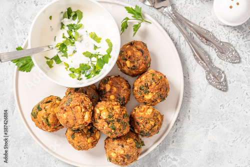 Fototapeta Naklejka Na Ścianę i Meble -  Homemade falafel close up. Chickpea balls with spices and yogurt with herbs on a gray concrete table.