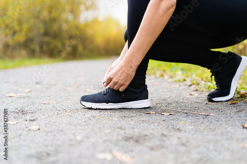 Running shoes runner woman tying laces for autumn run in forest park. Runner trying running shoes getting ready for run. Jogging girl exercise motivation heatlh and fitness