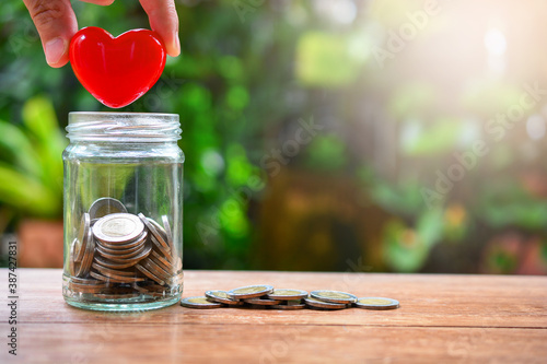 Konstfotografi putting heart model on saving bottle for concept donation and philanthropy