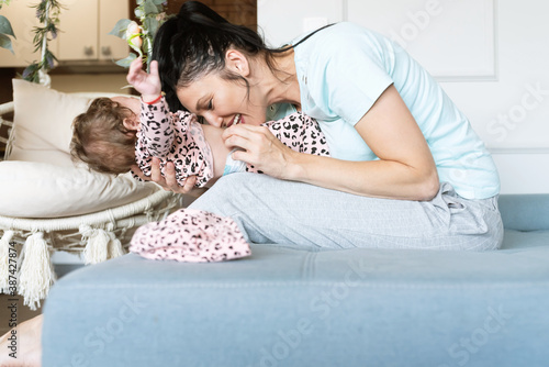 Mother tickling and having fun with baby girl at home photo