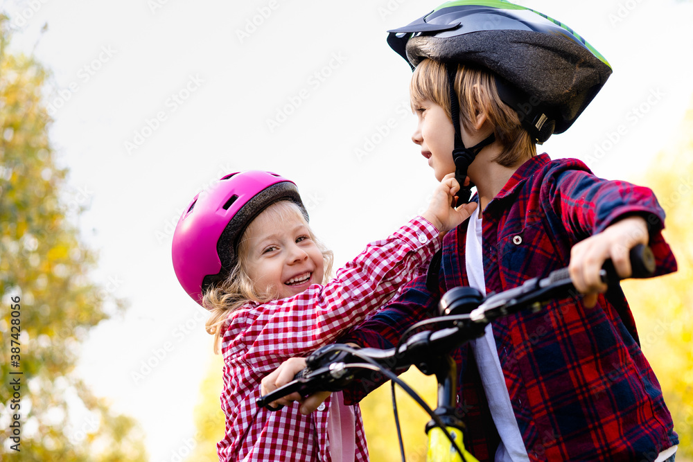 the brother helps the younger sister to put on and fasten a protective helmet for a Bicycle the brother helps the younger sister to put on and fasten a protective helmet for a Bicycle