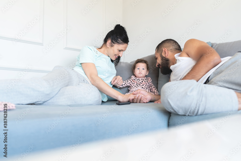 Loving parents having fun with adorable baby daughter on sofa at home Loving parents having fun with adorable baby daughter on sofa at home