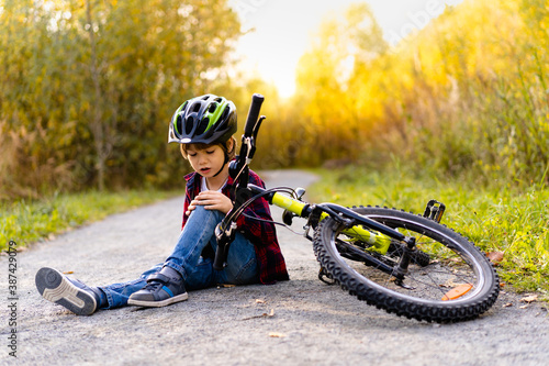 Konstfotografi a little boy in a helmet fell from a Bicycle in the Park in the fall, sports inj
