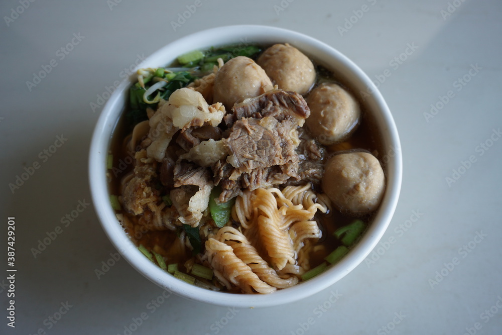 Thai Noodle (Tom Yum Noodles) has beef, meatballs, Ipomoea aquatica, Bean sprouts, in white bowl isolated on white background. Thai Noodle (Tom Yum Noodles) has beef, meatballs, Ipomoea aquatica, Bean sprouts, in white bowl isolated on white background.