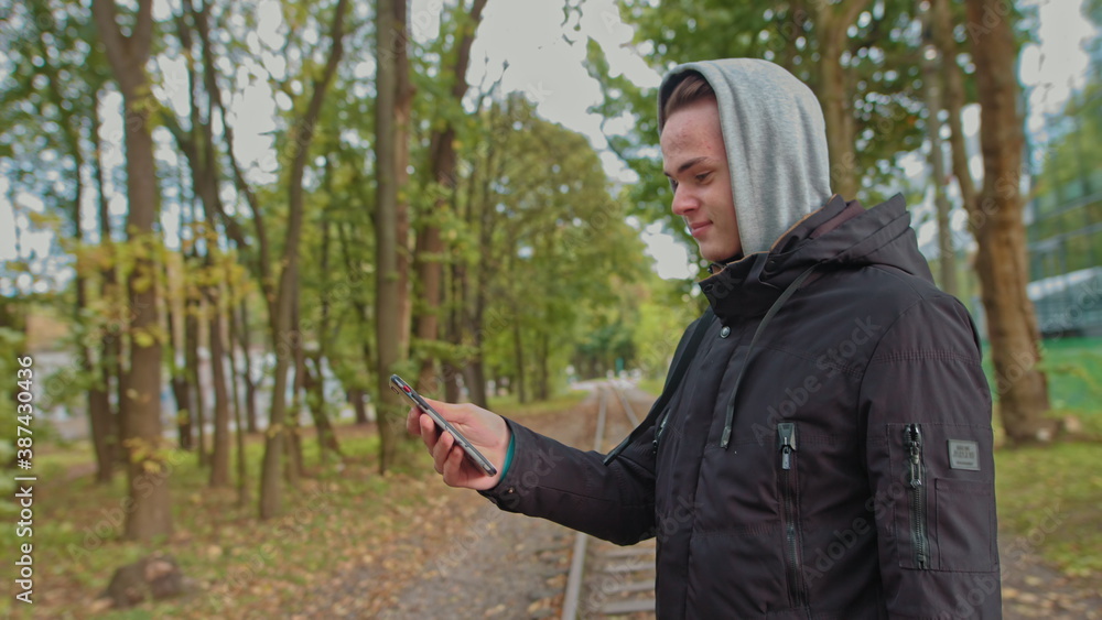 Nomophobia - People using the mobile phone. No-mobile-phone phobia. young guy talking on a video call on the street in the park. Life without a smartphone is not possible, communication with a slave Nomophobia - People using the mobile phone. No-mobile-phone phobia. young guy talking on a video call on the street in the park. Life without a smartphone is not possible, communication with a slave