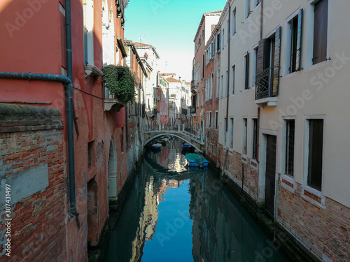 Pictures from Italy. Narrow canal in Venice with colorful houses and small bridge 