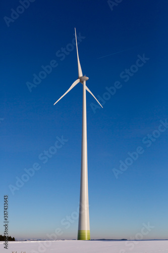 Wind turbine in winter on a field with blue sky