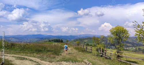 The girl with backpack walks along the road in the mountains. Yasinia. Carpathians. Ukraine. Europe