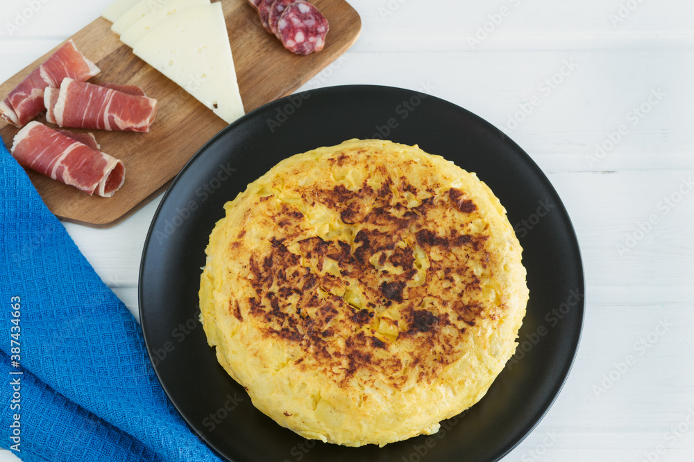 Spanish potato omelette on a black plate on a white background Copy space. Typical food concept. Spanish potato omelette on a black plate on a white background Copy space. Typical food concept.