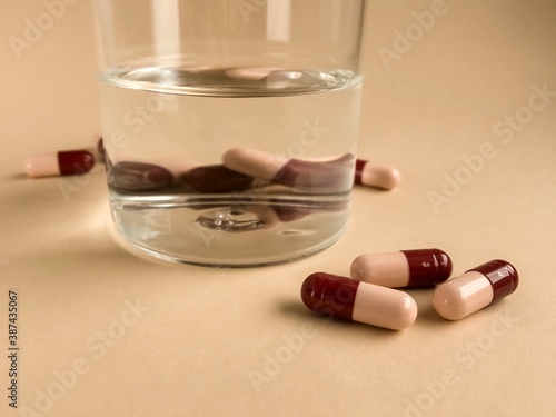 capsules with a glass of water, medicine on a beige background