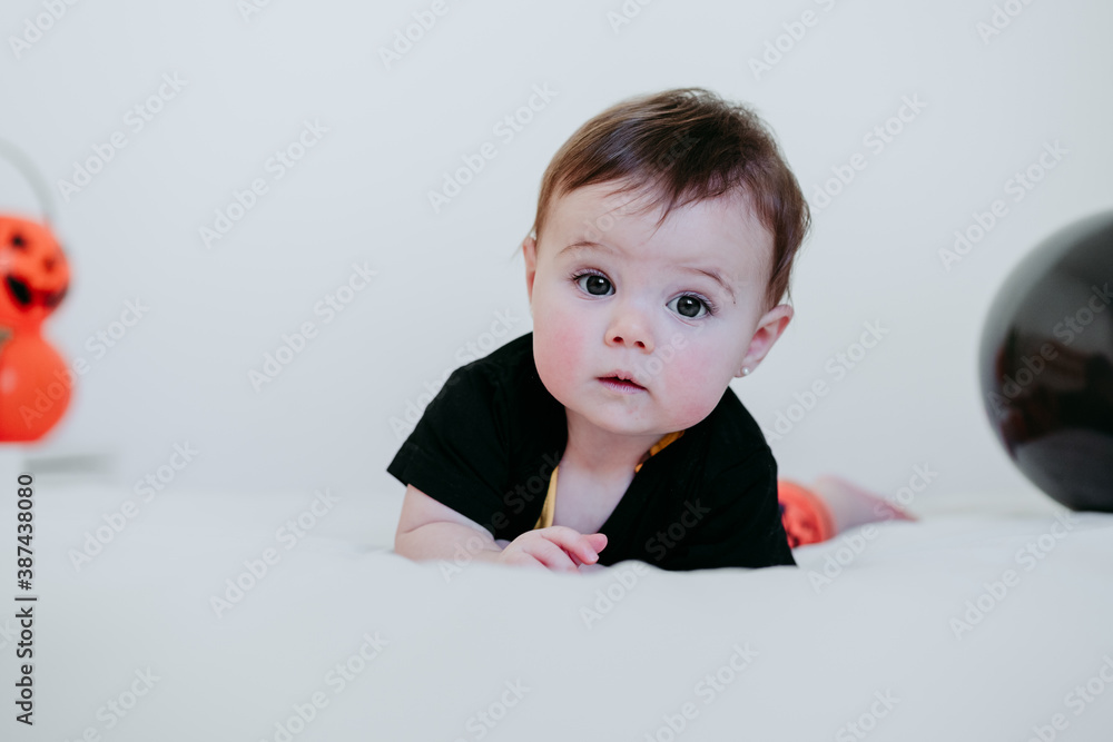 cute baby girl in halloween costume at home, sitting on bed with Halloween decoration, Lifestyle indoors cute baby girl in halloween costume at home, sitting on bed with Halloween decoration, Lifestyle indoors