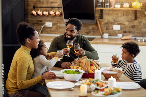 Happy black family toasting during Thanksgiving lunch in dining room.