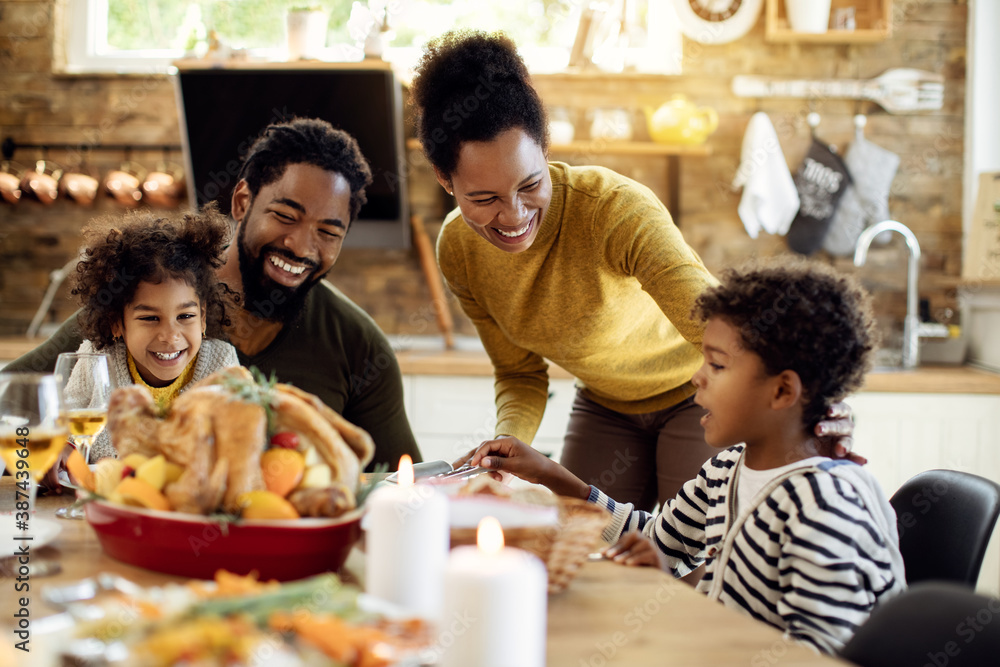 Happy African American family having fun during Thanksgiving lunch at dining table. - obrazy, fototapety, plakaty 