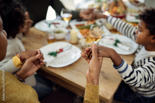 Close-up of African American family saying grace before Christmas meal in dining room.