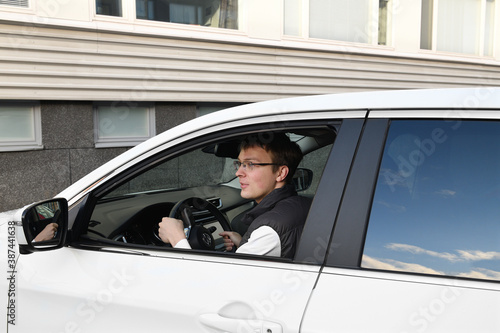 Young handsome man with glasses driving white car © valeriyap