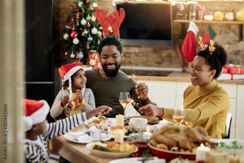 Happy black family having fun with sparklers during Christmas lunch in