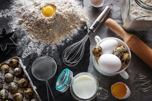 baking products and utensils on a black background, milk, eggs, flour