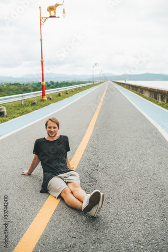 Man sitting on the road at Krasiao dam. Suphanburi province, Thailand photo