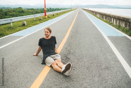 Man sitting on the road at Krasiao dam. Suphanburi province, Thailand photo