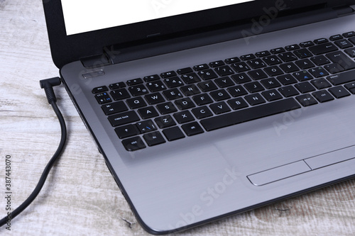 Laptop, computer is charging from a 220-volt outlet on a desk near the wall. Energy, accumulation. Mockup