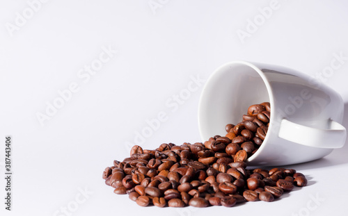 Isolated coffee beans (selective focus on coffee beans) with ceramic cup, white background.