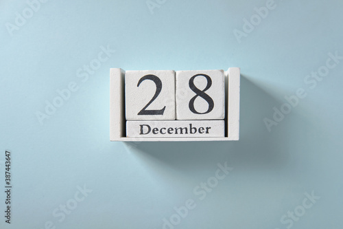 Wooden white calendar on blue background, date 28 December. © grek881
