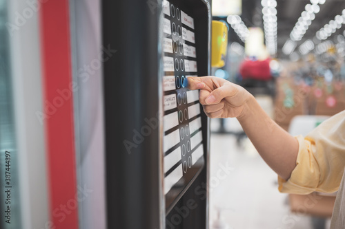 Asian woman buying can drink from vending machine in airport photo